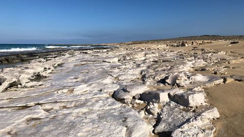 Scenic view of rocks on beach against clear sky