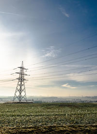 Electricity pylon on field against sky