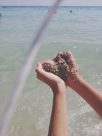 Close-up of hand holding ice cream against sea