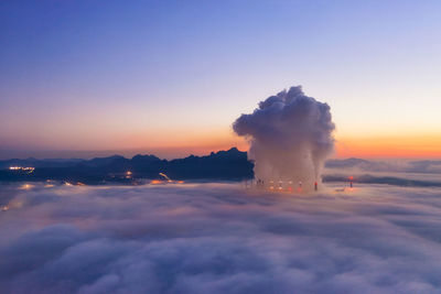 Factory emitting smoke against sky during sunset