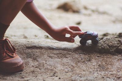 Cropped image of boy playing with toy car