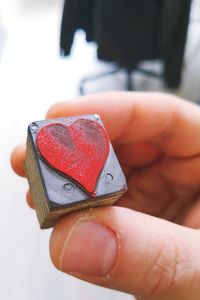 Close-up of hand holding metal cube with heart shape