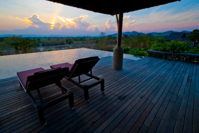 Chairs and table by sea against sky at dusk