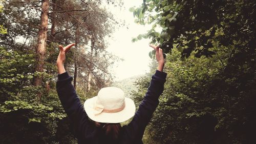 Rear view of person standing by plants in forest