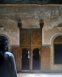 Rear view of man standing against door of building