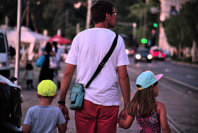 Rear view of man son and daughter standing on footpath