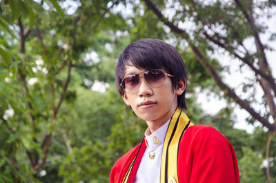 Portrait of man wearing sunglasses standing against trees