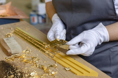 Mature woman decorating frame while standing at workbench in workshop