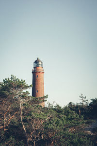 Lighthouse by building against clear sky