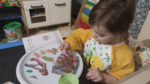 High angle view of girl holding paper at home