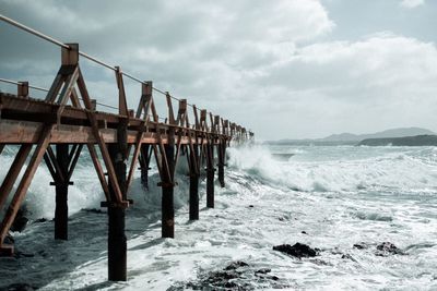 Pier on sea against cloudy sky