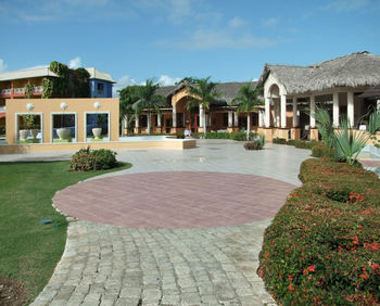 Footpath by swimming pool in building against sky