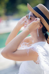 Midsection of woman holding hat while sitting outdoors