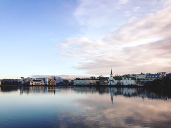 Buildings by river against sky in city