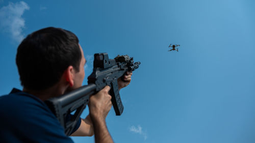 Low angle view of man photographing against sky