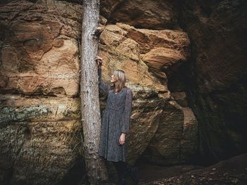 Woman standing on rock against tree trunk