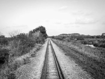 Empty railroad track on field against sky