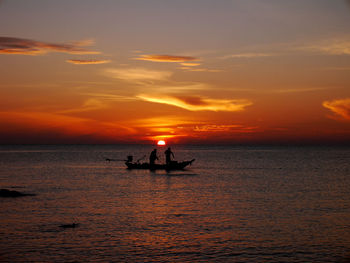 Silhouette boat in sea against orange sky