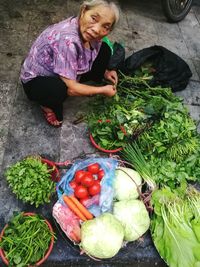 High angle view of mature woman selling vegetables at market