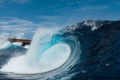 Waves splashing on shore against blue sky