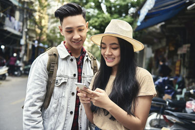 Happy young man using mobile phone in city