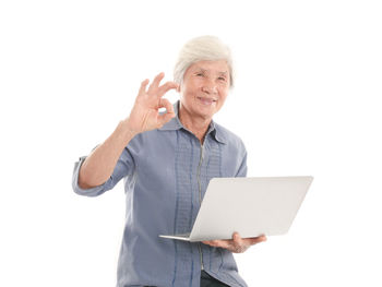 Portrait of senior woman using laptop against white background