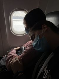 Teenage girls embracing and sleeping in airplane