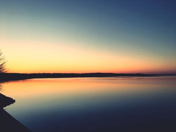 Scenic view of lake against clear sky during sunset