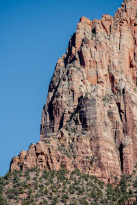 Low angle view of rock formation against clear blue sky