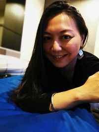 Portrait of a smiling young woman sitting on bed