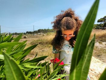 Woman standing by plants on field against sky