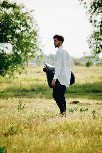 Man holding saddle on field