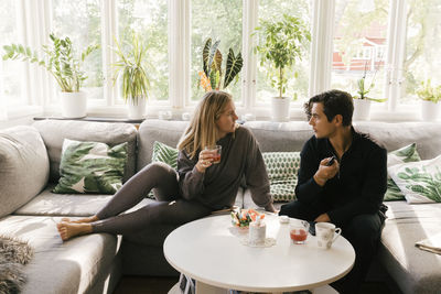 Worried couple talking to each other while sitting on sofa in living room