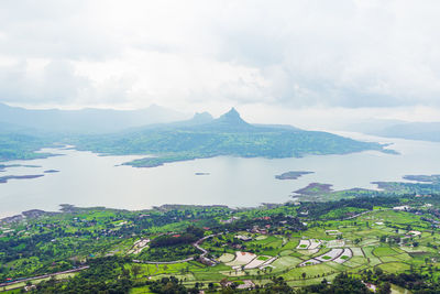 Scenic view of lake by townscape against sky