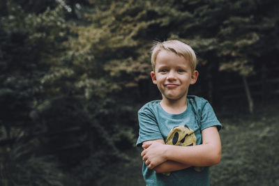 Portrait of confident boy with arms crossed standing at park