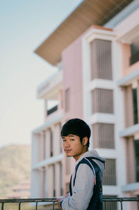 Portrait of young man standing against building