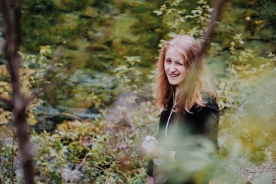 Portrait of smiling young woman in forest