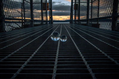 Metal fence by road against sky