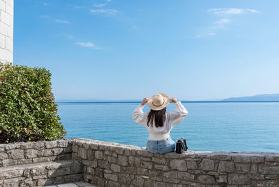 Full length rear view of man standing by sea against sky