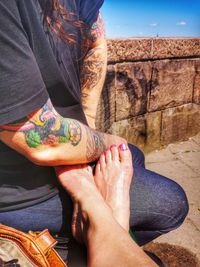 Low section of woman sitting on wall
