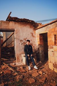 Man standing by abandoned building against sky