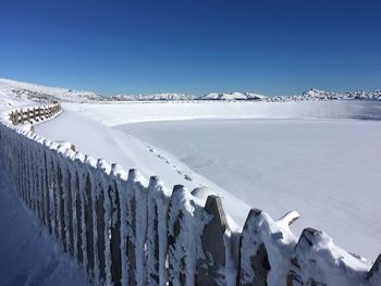 Panoramic view of snow covered landscape against clear blue sky