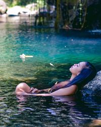 Side view of woman lying in swimming pool