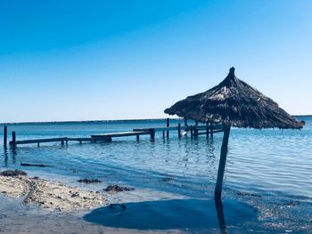 Gazebo on beach against clear blue sky