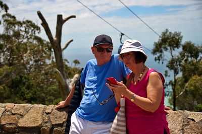 Senior couple standing on the viewpoint and using mobile phone