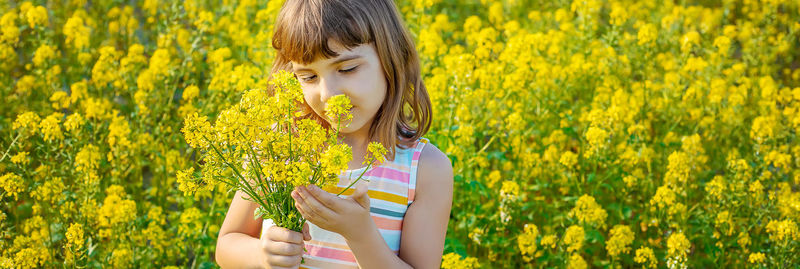 Cute girl holding flowers while standing in field