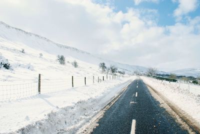 Snow covered landscape against cloudy sky