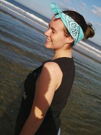 Side view of smiling teenage girl standing at beach during summer