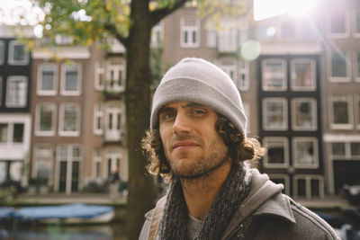 Portrait of man wearing knit hat with buildings in background