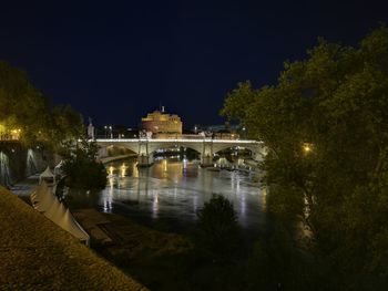 Illuminated building by lake at night